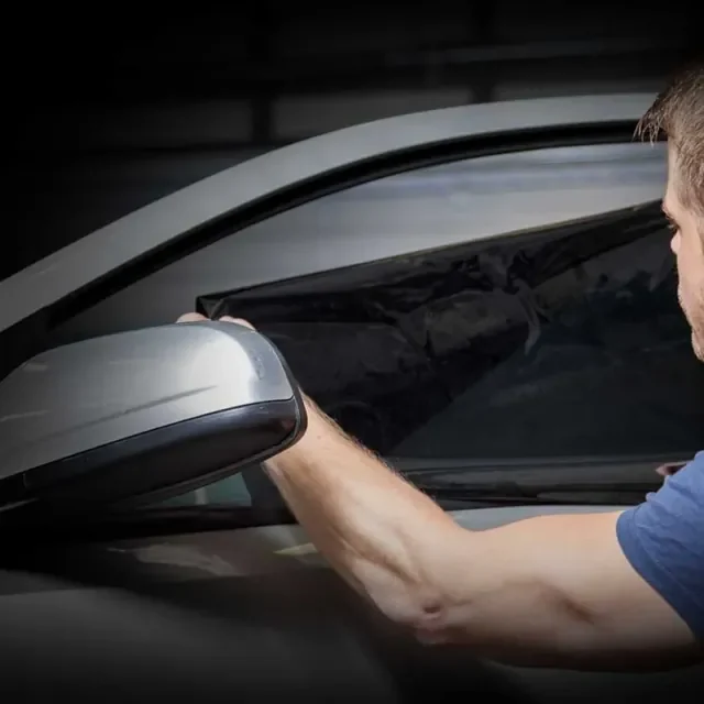 Installer fitting ceramic window tint film to a car door window at Artec Automotive